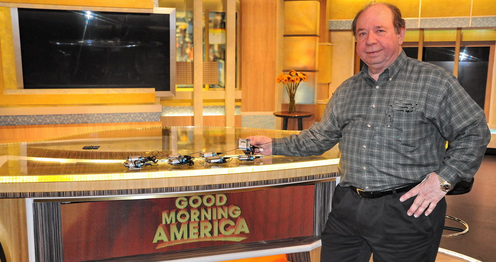 A man standing in front of a bar with coffee cups on it.