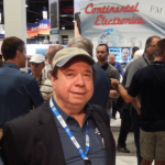 A man in a hat and jacket standing next to other people.