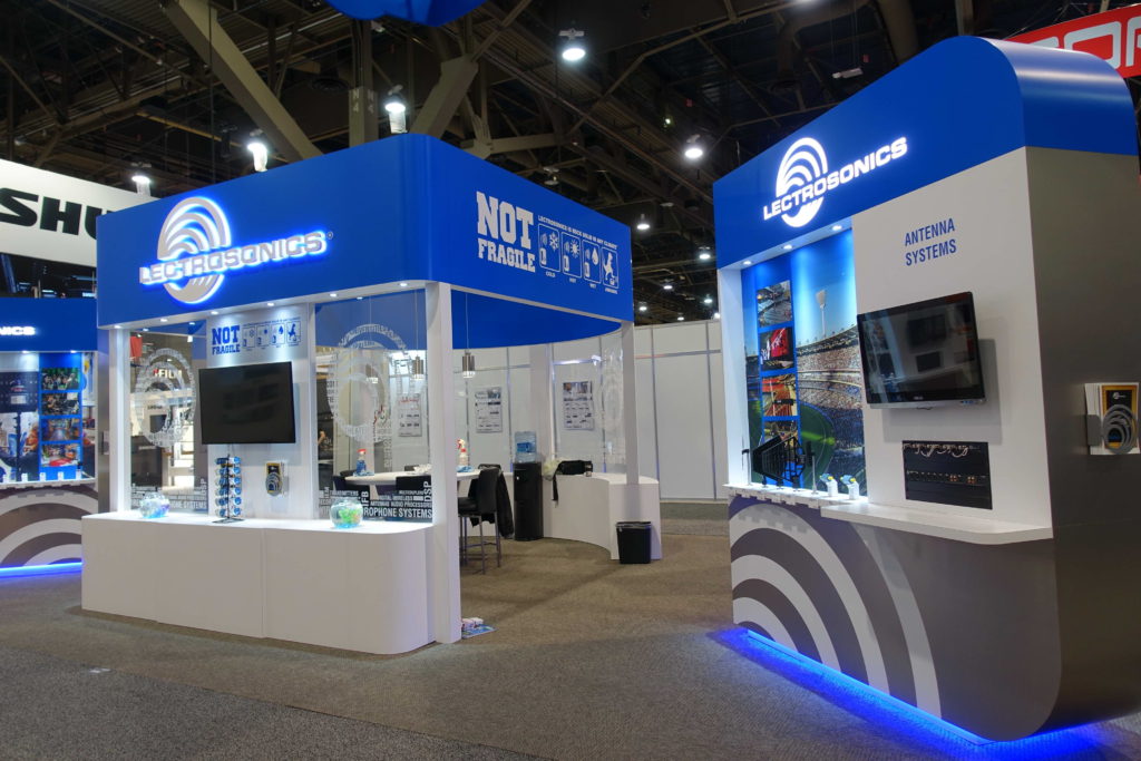 A booth with blue and white walls, and a large display of electronics.