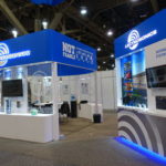 A booth with blue and white walls, and a large display of electronics.