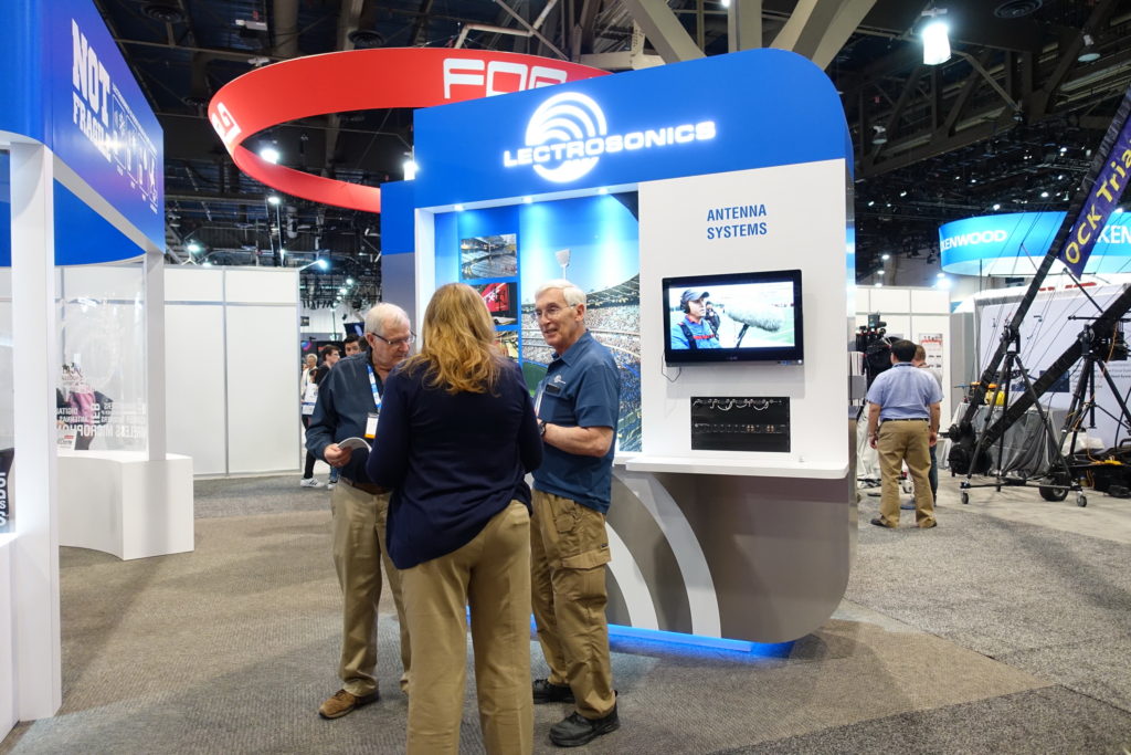 A group of people standing around in front of a booth.