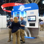 A group of people standing around in front of a booth.
