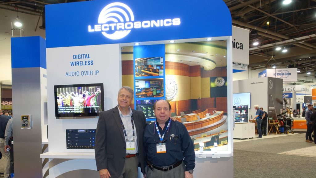 Two men standing in front of a lectrosonics booth.