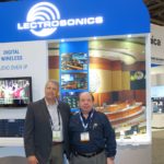 Two men standing in front of a lectrosonics booth.