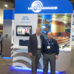 Two men standing in front of a large sign.
