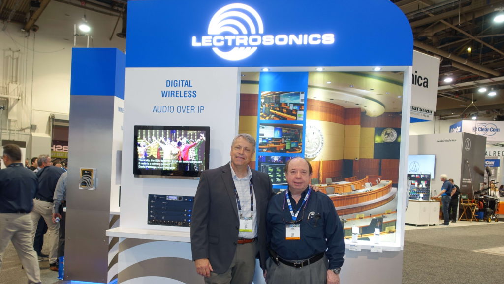 Two men standing in front of a lectrosonics booth.