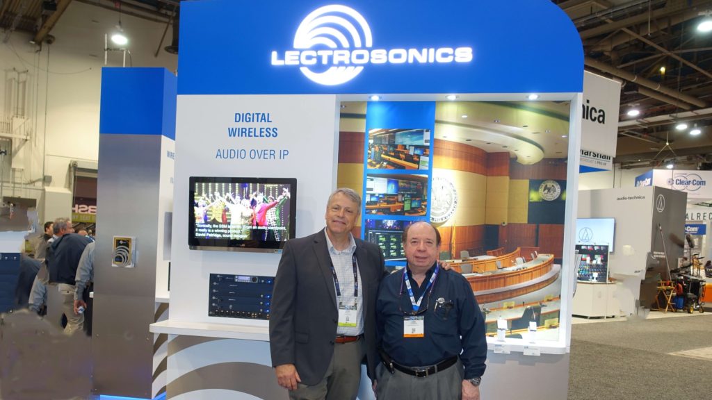 Two men standing in front of a lectrosonics booth.