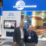 Two men standing in front of a lectrosonics booth.