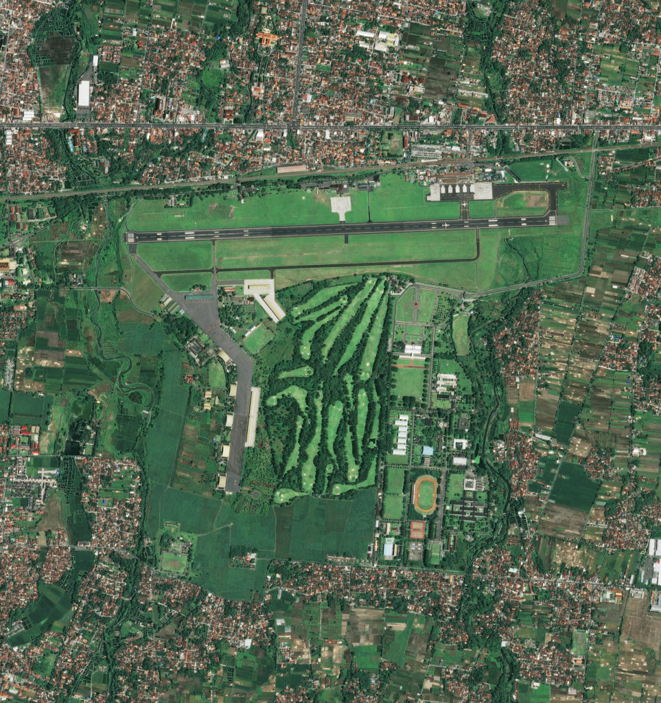 A satellite image of an airport with golf course and trees.